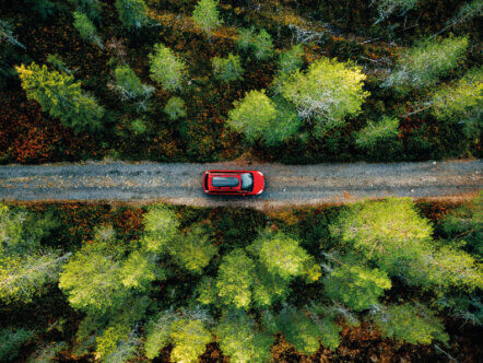 Aerial view of red car for traveling with a roof rack on a country road in Finland