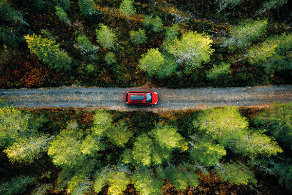 Aerial view of red car for traveling with a roof rack on a country road in Finland