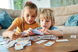 Portrait of brother and sister having fun together playing board game at home