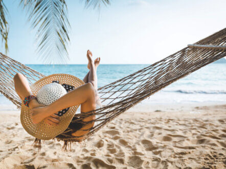 Holiday image, person in hammock on sandy beach. Source: AdobeStock_435196429