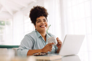 Wide angle shot of woman sitting on table with coffee mug and laptop. Woman taking break while working from home.