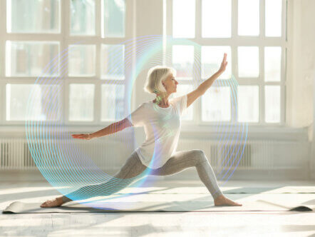 A middle-aged woman performing a yoga pose on a mat in a bright, airy studio. She is wearing comfortable, form-fitting yoga attire and has a serene expression on her face.