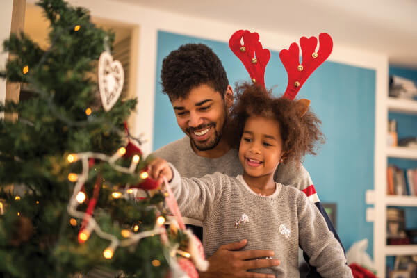 Dad and daughter decorating Christmas tree together.