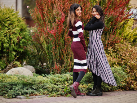 Portrait of two girls dressed in stripes posed near bushes