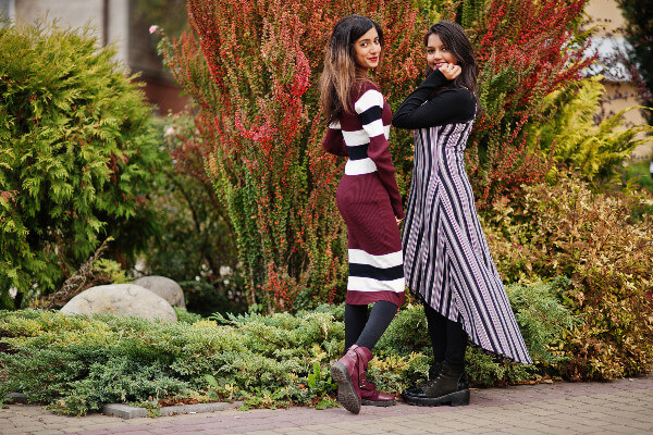 Portrait of two girls dressed in stripes posed near bushes